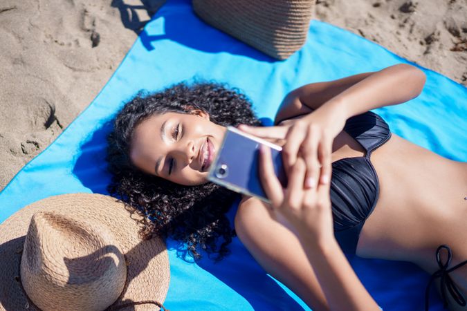 A cheerful young woman is taking a selfie on the beautiful beach using her smartphone
