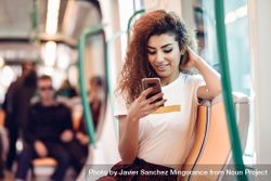 Arab woman sitting in subway carriage checking phone 0JX7w4