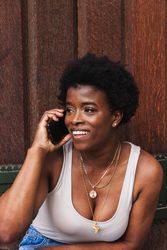 Smiling Black woman talking on smartphone sitting near building