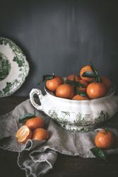 Orange tangerines in ceramic ornamental bowl on wooden table
