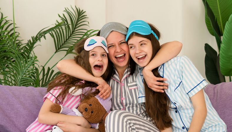 Playful moment with mother and daughters in pajamas.