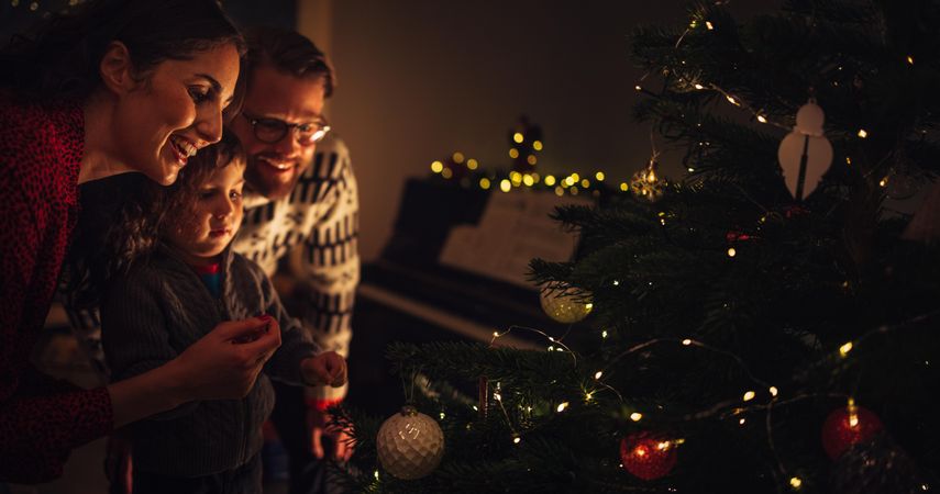 Parents with son decorating Christmas tree at home