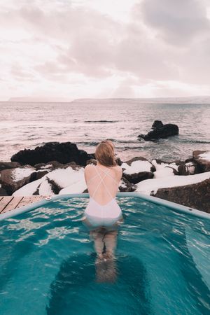 Woman sitting in pool near stones