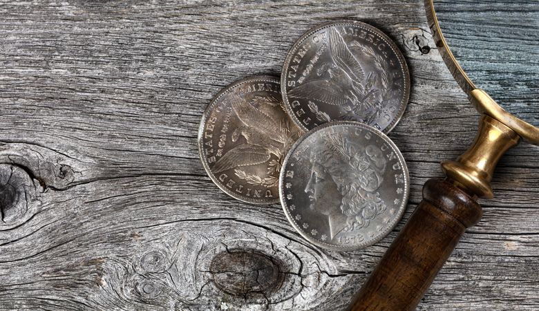 Morgan silver dollars with magnify glass on wood