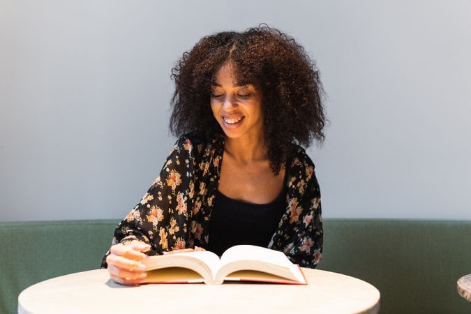 Black woman reading book at cafe table