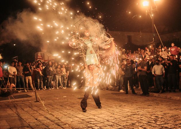 Man holding female effigy with fireworks shooting off
