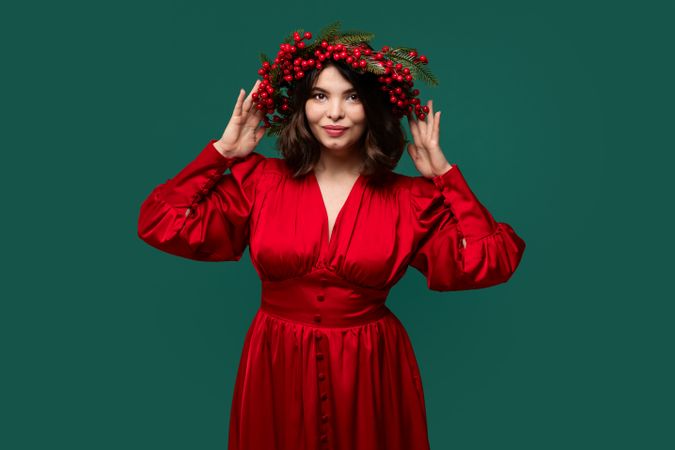 Woman in red dress adjusting berry wreath on head