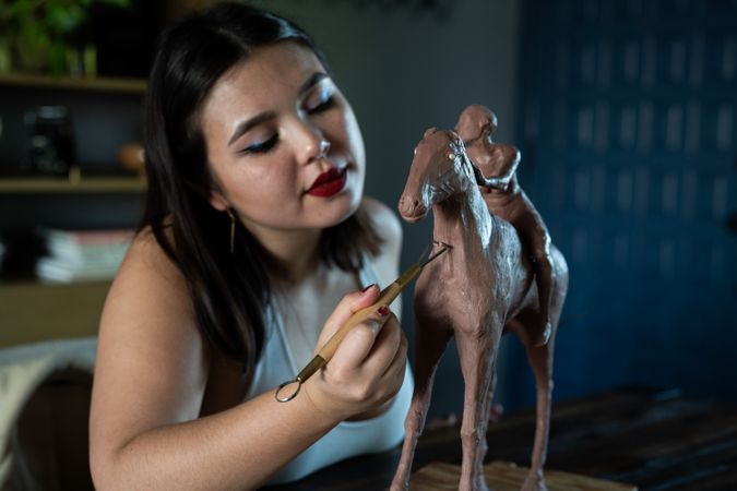 Close Up of woman working on clay horse sculpture