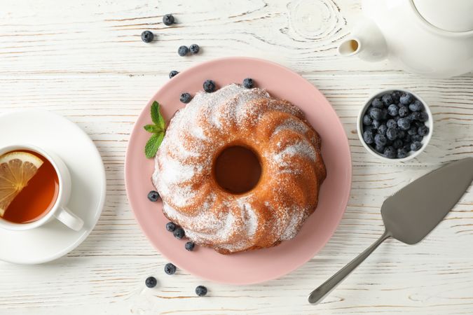 Cake with powder sugar and blueberry on wooden background, top view