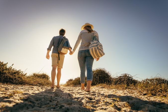 Couple on vacation walking together on sand holding hands