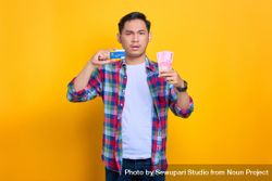 Upset Asian man holding credit card and cash in studio shoot 5reQZ0