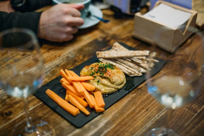 Plate of carrots, pita and hummus on a wooden table