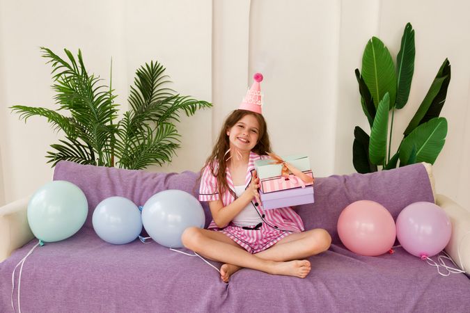 Young girl celebrating birthday at home with gifts and balloons.