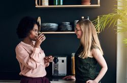 Two female businesswomen getting a drink in the office break room