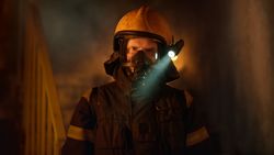 Portrait of fireman with helmet and flashlight with smoke behind