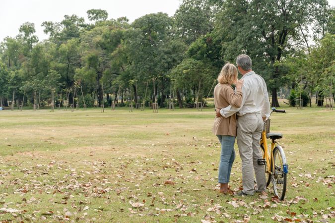 Back of mature man and woman standing in park