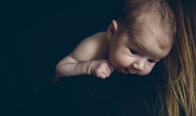 Baby holding on to her mother's shoulder