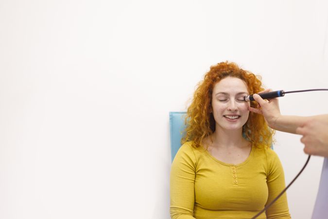 Woman smiling with eye pressure instrument to her face