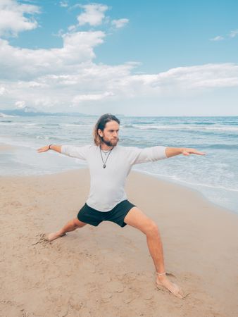 Man training yoga on beach