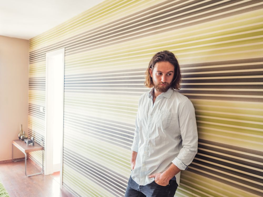Handsome male standing with hand in pockets in modern room