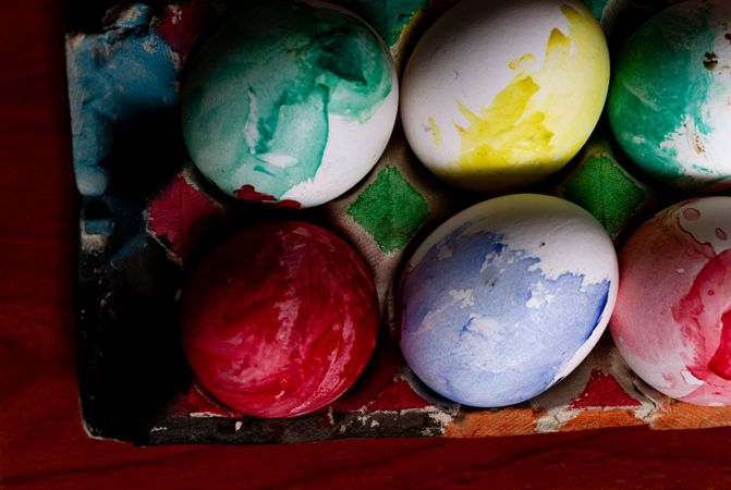 Set of painted Easter eggs in container on table