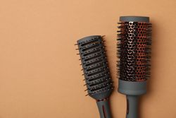 Hair brushes on brown background, space for text