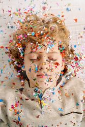 Preschool boy with closed eyes covered with colorful confetti