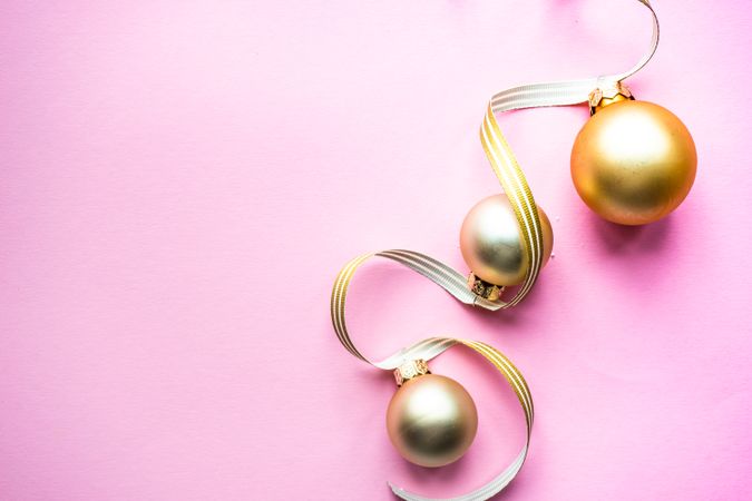 Gold Christmas baubles on pink background