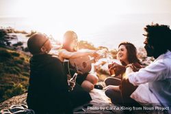 Group of friends laughing outside with drinks and guitar 6beP4d