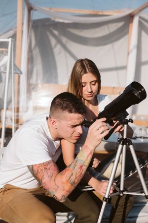 Young couple using astronomical telescope
