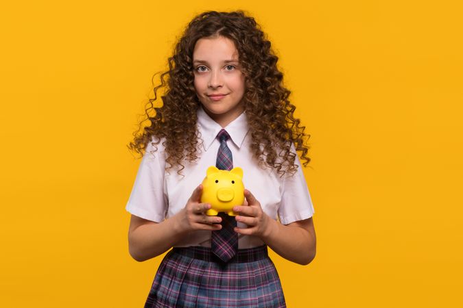 Smiling girl holding yellow piggy bank