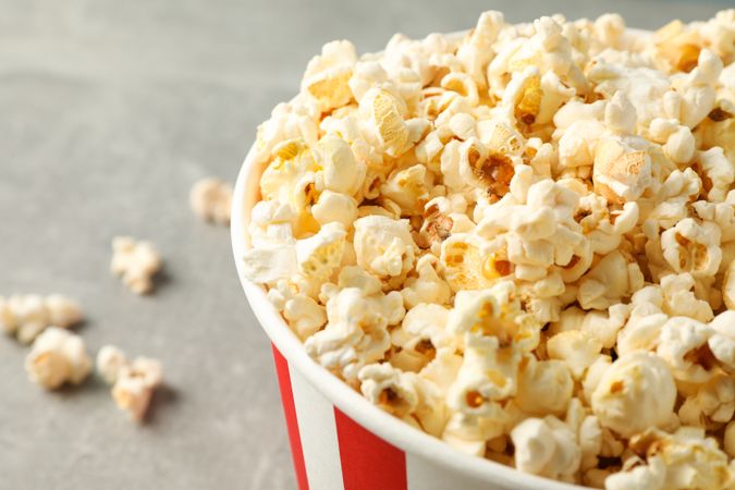 Bucket with popcorn on grey background, space for text