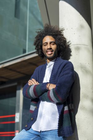 Looking up at Black man standing with arms crossed on sunny day