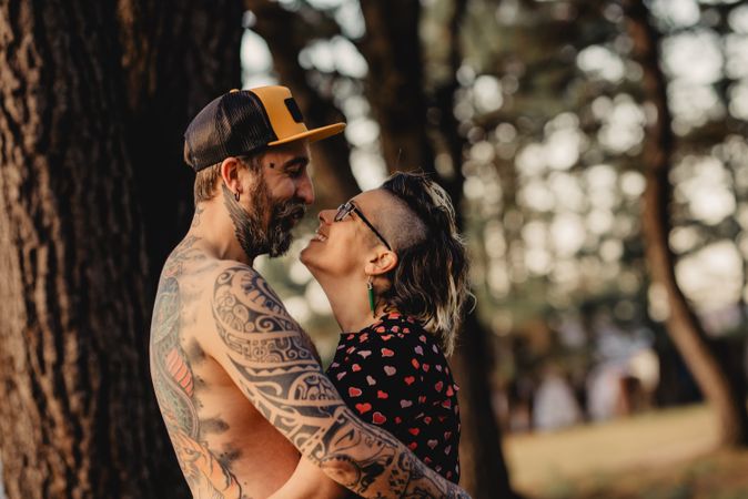 Happy couple hugging near tree in park