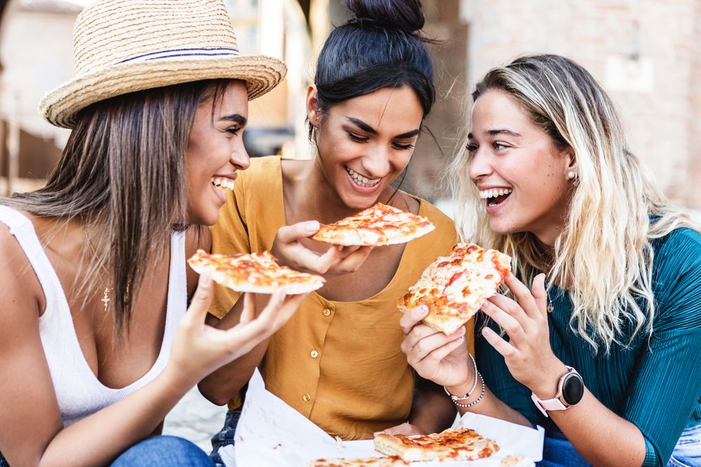 Diverse group of female friends enjoying take away pizza outside
