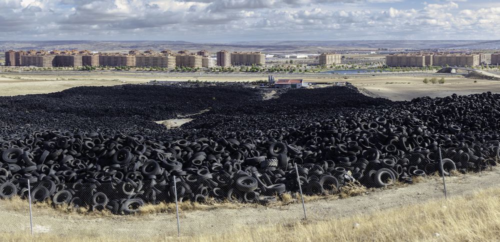 Heap of old tires between field near city
