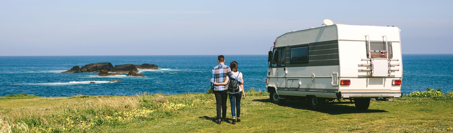 Couple taking a walk near the coast with a camper