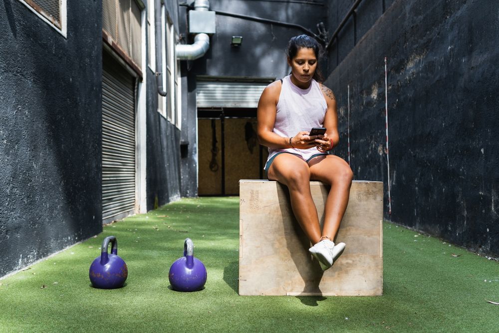 Hispanic woman browsing smartphone on jump box