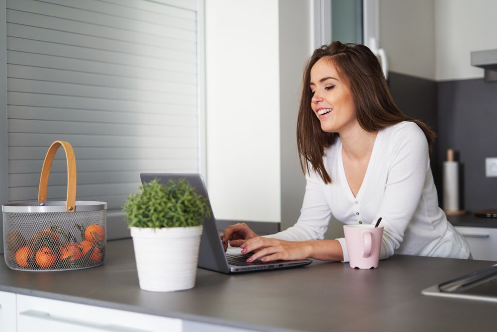 Smiling woman browsing on laptop and sitting on settee