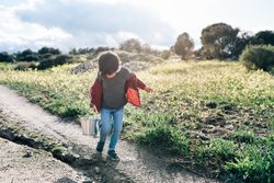 Kid with bucket walking on rural road