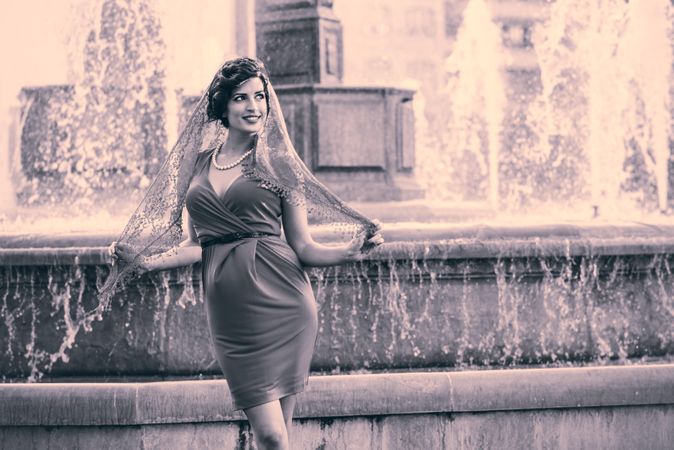 Elegant woman standing by European city fountain