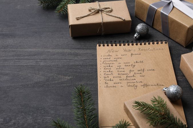 Notepad with list and gift boxes on gray wooden background, space for text