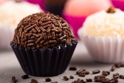 Close up of chocolate truffles with sprinkles and coconut truffles on marble table