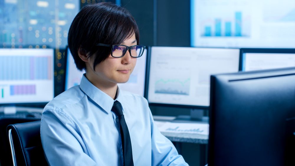 In the Data Mining Center Statistician sits at His Workstation Surrounded with Monitors Displaying Data and Graphs.