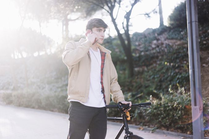 Man walking with bike while looking down at mobile phone