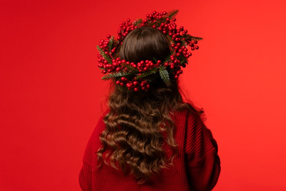 Teen girl with long curly hair wearing Christmas berry wreath.
