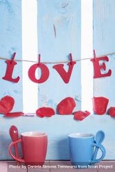 Cups with spoons and the word love hung on a blue fence 4dMZEb