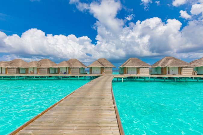 Overwater bungalows connected with walkway over blue tropical waters