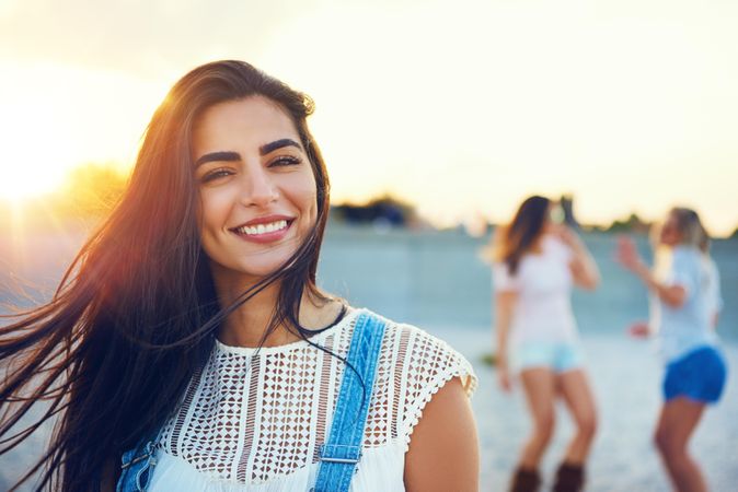 Smiling brunette woman with friends in background on beach