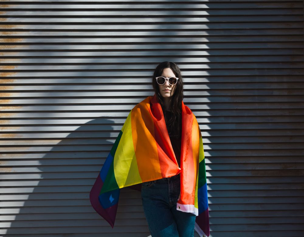 Woman posing happily with a rainbow flag